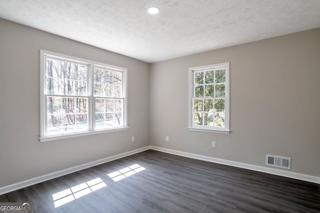 empty room featuring visible vents, baseboards, and dark wood-type flooring