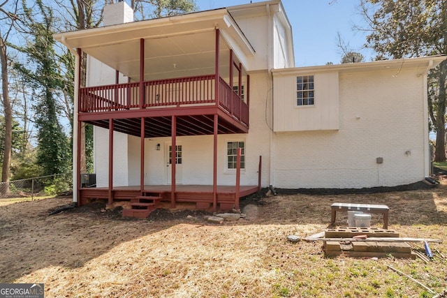 rear view of house with brick siding, a chimney, and fence
