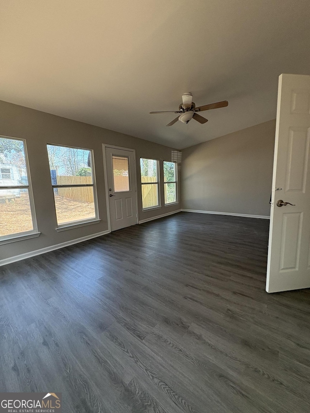 unfurnished room featuring baseboards, dark wood-style floors, and a ceiling fan