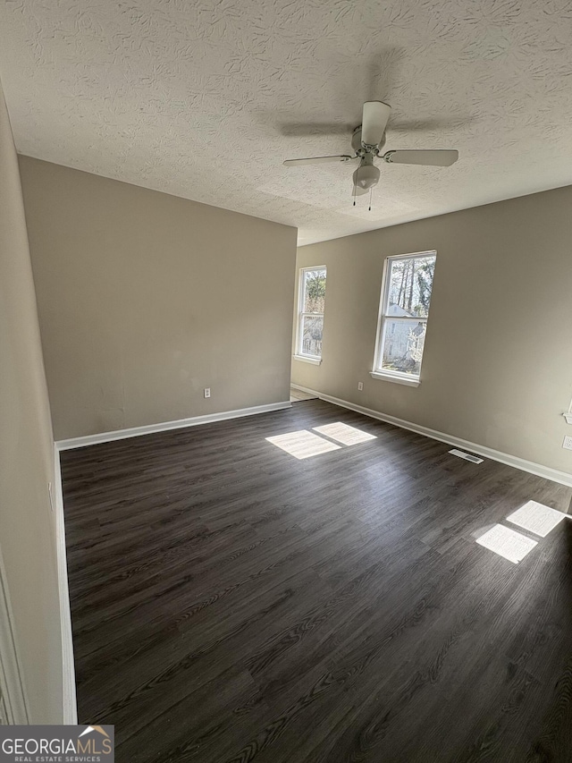 empty room with baseboards, a textured ceiling, dark wood-style floors, and a ceiling fan