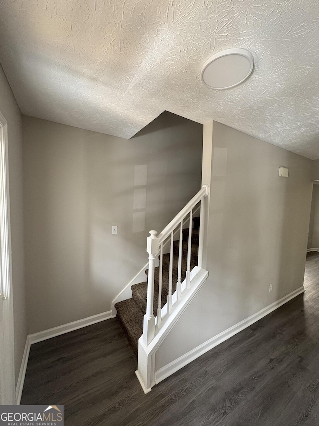 staircase with baseboards, a textured ceiling, and wood finished floors