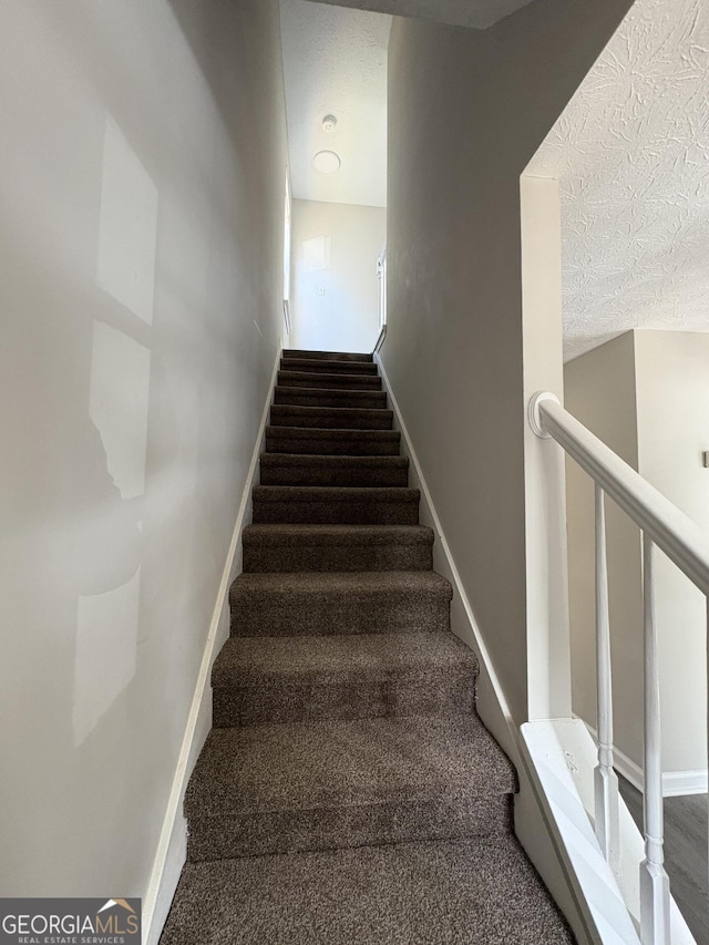 staircase featuring baseboards and a textured ceiling