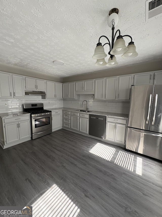 kitchen with visible vents, a sink, stainless steel appliances, under cabinet range hood, and tasteful backsplash