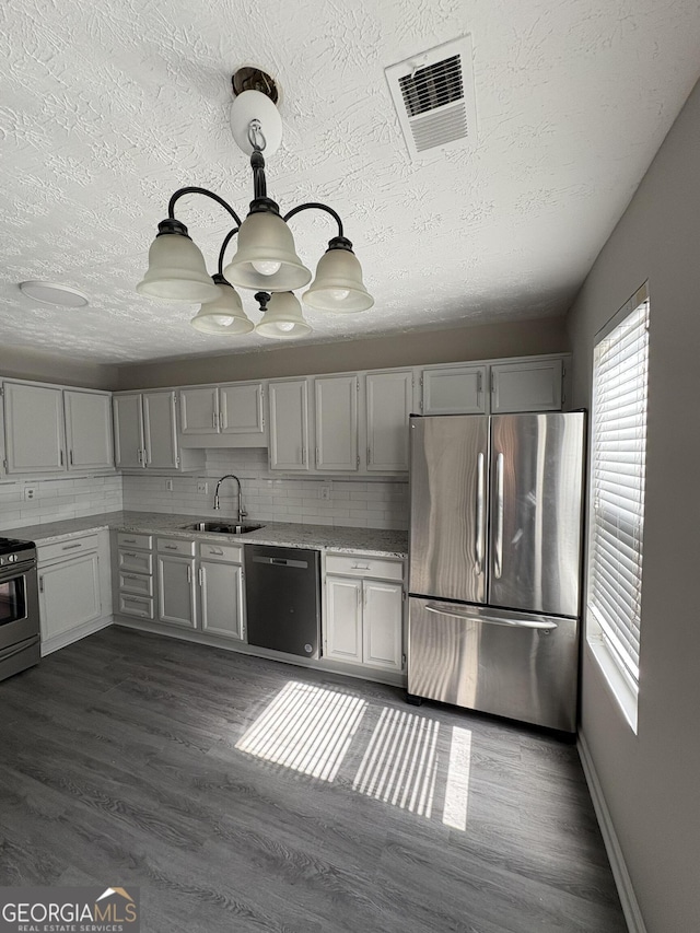 kitchen with visible vents, a sink, black gas range, freestanding refrigerator, and dishwashing machine