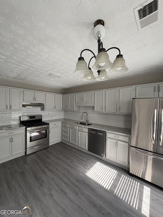 kitchen featuring visible vents, a sink, stainless steel appliances, under cabinet range hood, and backsplash