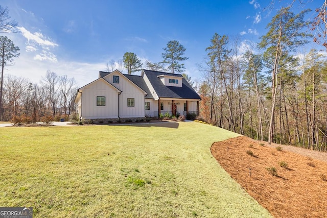 modern farmhouse featuring board and batten siding, covered porch, and a front yard