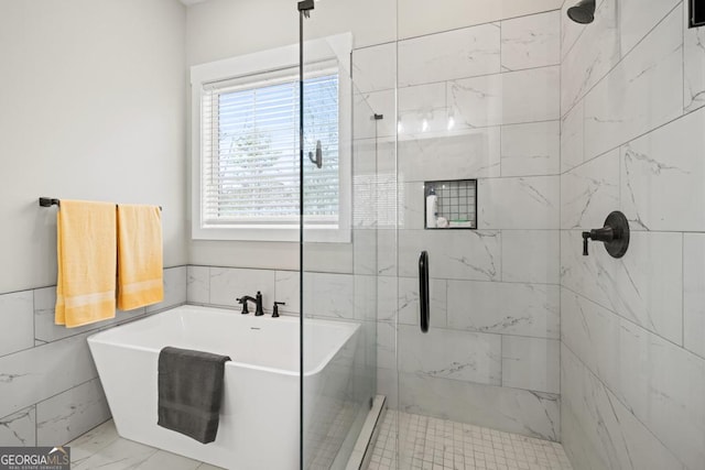 bathroom with tile walls, a freestanding tub, and a stall shower