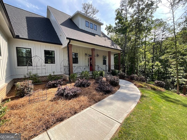 212 Cardiff Ct, Ball Ground, GA 30107 - modern farmhouse style home with covered porch, board and batten siding, a front yard, and a shingled roof