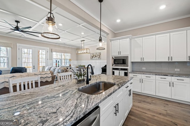 kitchen with crown molding, appliances with stainless steel finishes, wood finished floors, coffered ceiling, and a sink