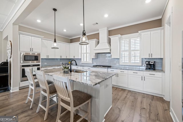 212 Cardiff Ct, Ball Ground, GA 30107 - kitchen featuring appliances with stainless steel finishes, custom range hood, a sink, white cabinetry, and crown molding