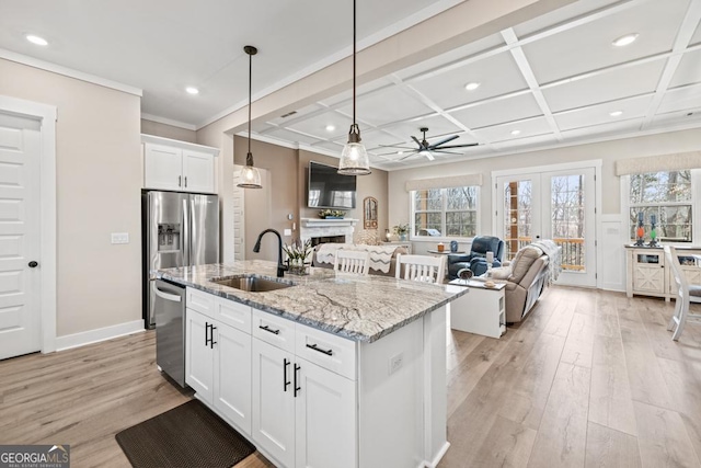 kitchen with a sink, coffered ceiling, light wood-style floors, appliances with stainless steel finishes, and a fireplace