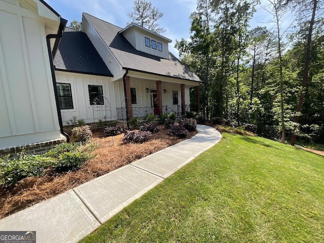 212 Cardiff Ct, Ball Ground, GA 30107 - view of front of property featuring covered porch, board and batten siding, a front lawn, and a shingled roof