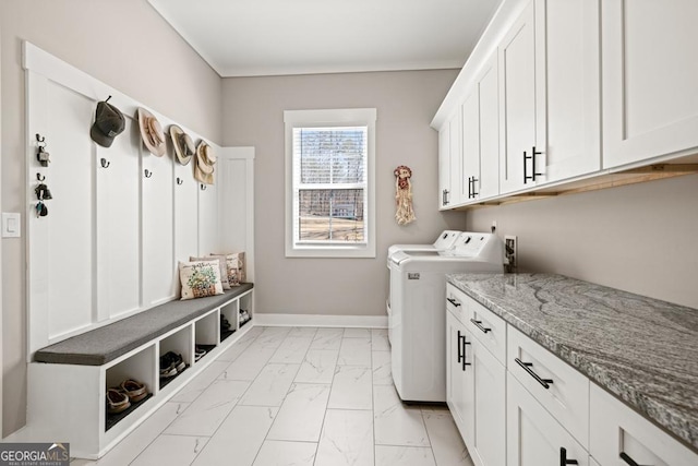 washroom featuring baseboards, washing machine and clothes dryer, cabinet space, crown molding, and marble finish floor