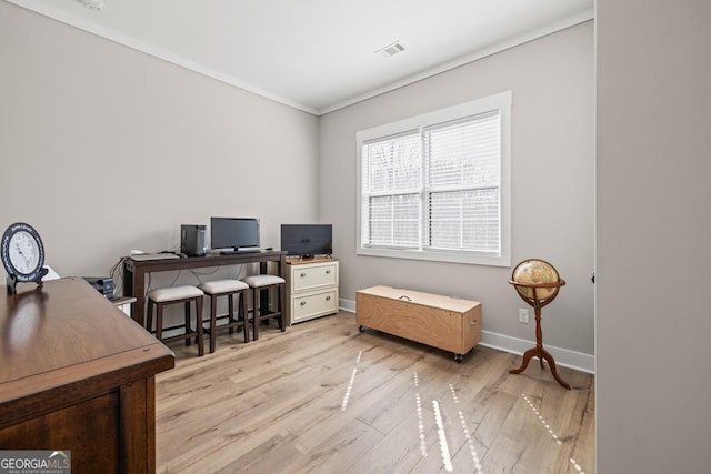 home office with visible vents, baseboards, light wood-style floors, and ornamental molding