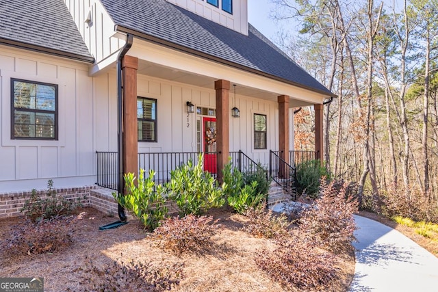 view of exterior entry featuring a porch, board and batten siding, and a shingled roof