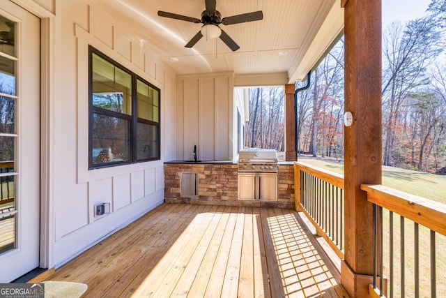 wooden terrace featuring an outdoor kitchen, a sink, a ceiling fan, and grilling area