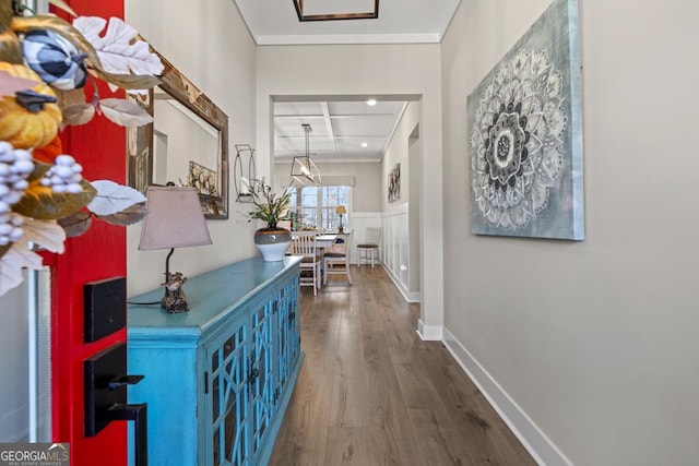 hallway with wood finished floors, baseboards, coffered ceiling, and ornamental molding