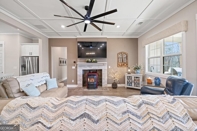 living area featuring coffered ceiling, baseboards, ceiling fan, and wood finished floors