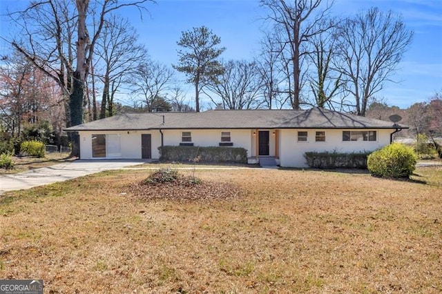 ranch-style house featuring an attached garage, concrete driveway, and a front yard