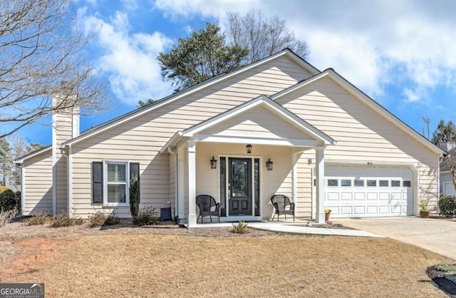 view of front of property with an attached garage, a front yard, covered porch, a chimney, and driveway