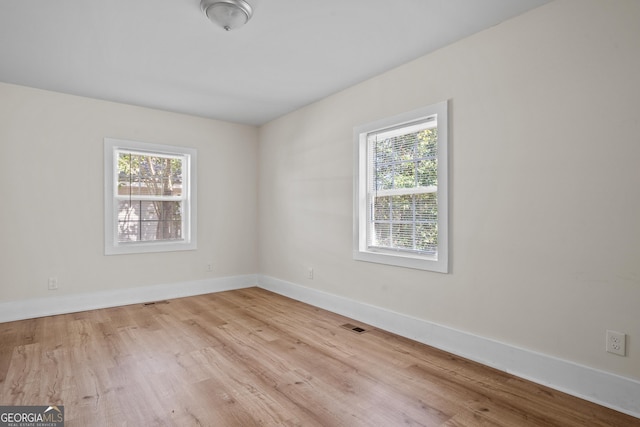 spare room with baseboards and wood finished floors