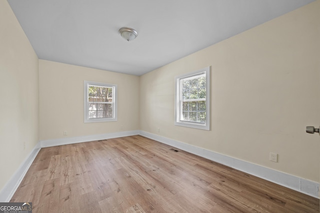 empty room with visible vents, baseboards, and wood finished floors