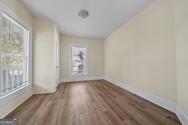 unfurnished room with plenty of natural light, baseboards, and wood finished floors