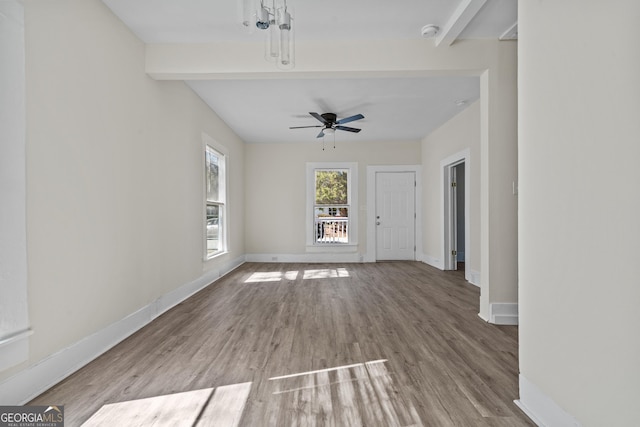 interior space with beamed ceiling, a ceiling fan, baseboards, and wood finished floors