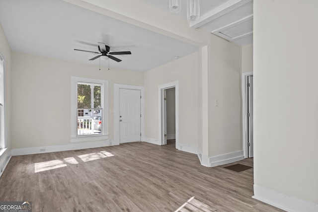 unfurnished living room featuring a ceiling fan, visible vents, wood finished floors, and baseboards