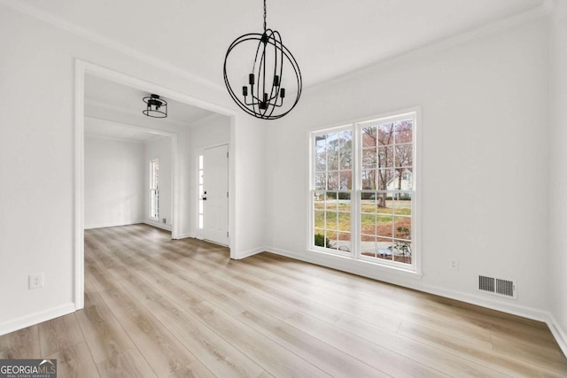 unfurnished dining area with wood finished floors, visible vents, baseboards, an inviting chandelier, and crown molding