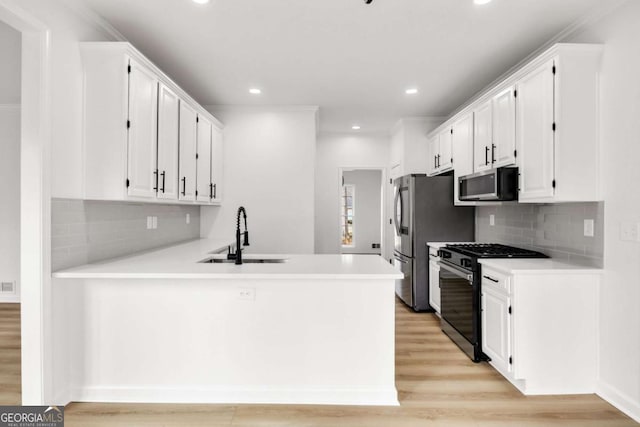 kitchen featuring appliances with stainless steel finishes, white cabinetry, and a sink