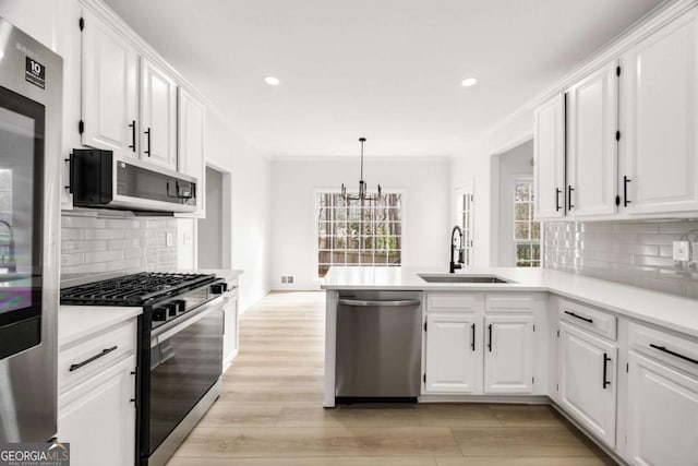 kitchen with a wealth of natural light, appliances with stainless steel finishes, white cabinetry, and a sink