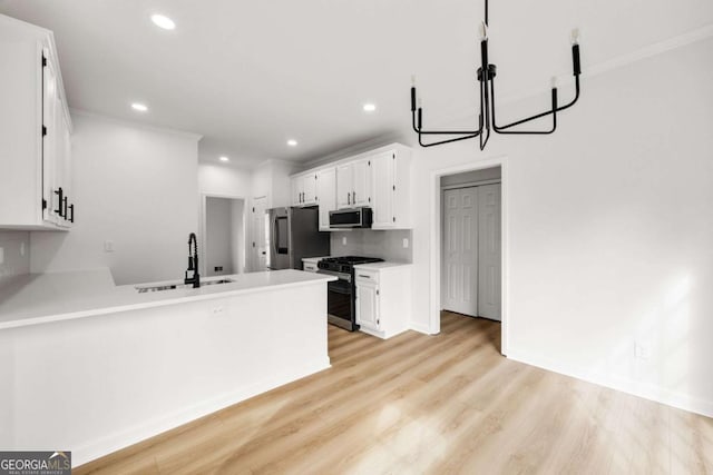 kitchen with a sink, appliances with stainless steel finishes, a peninsula, white cabinets, and light wood finished floors