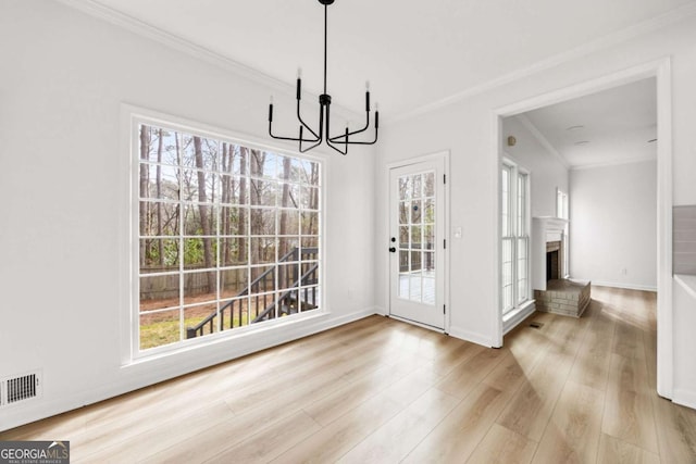 unfurnished dining area with visible vents, a fireplace, crown molding, and wood finished floors