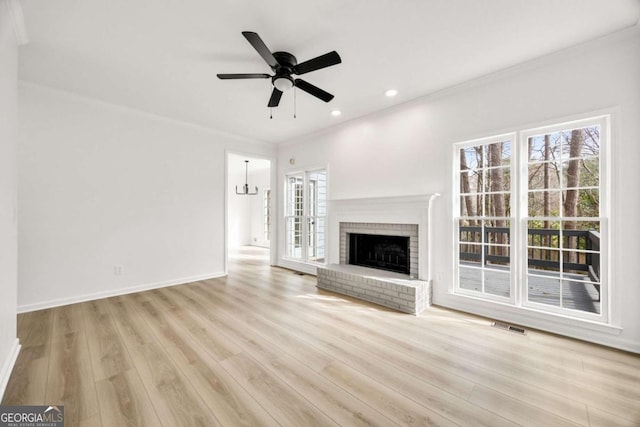 unfurnished living room featuring a healthy amount of sunlight, visible vents, light wood finished floors, and ornamental molding