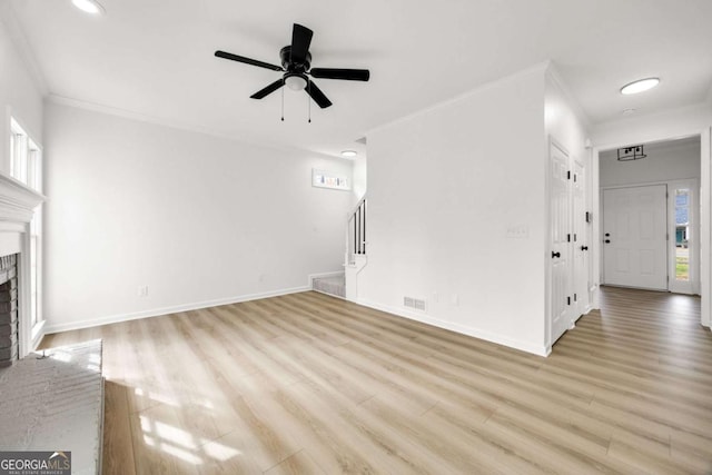 unfurnished living room featuring visible vents, crown molding, stairs, a fireplace, and wood finished floors