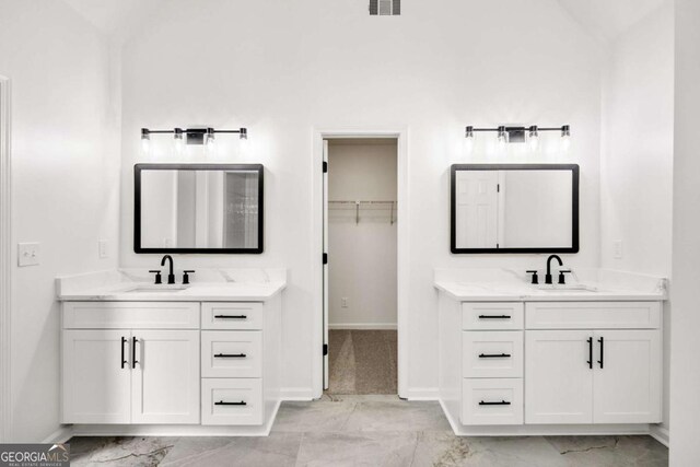 bathroom with two vanities, marble finish floor, and a sink