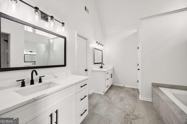 bathroom featuring a sink, marble finish floor, two vanities, and a washtub