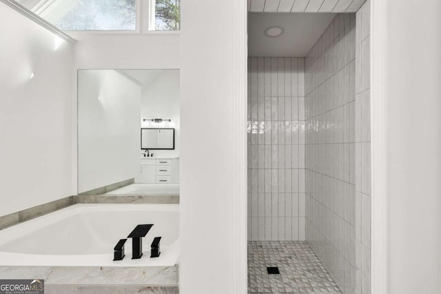 bathroom featuring tiled shower, a bath, and vanity