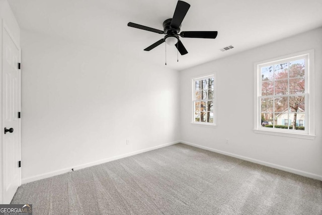 carpeted empty room with visible vents, baseboards, and ceiling fan