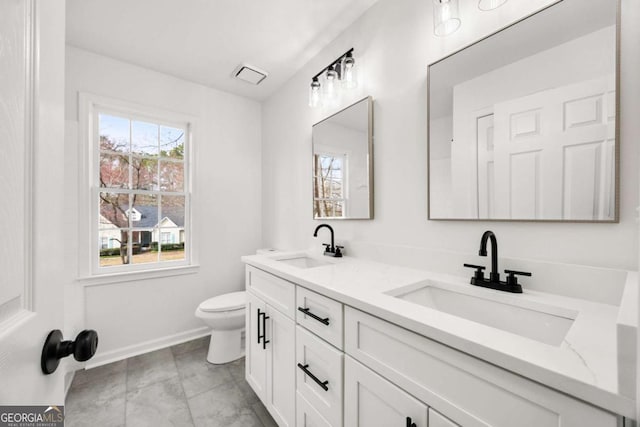 bathroom featuring double vanity, toilet, visible vents, and a sink