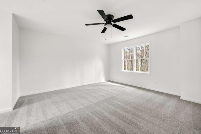 carpeted spare room featuring visible vents, baseboards, and ceiling fan