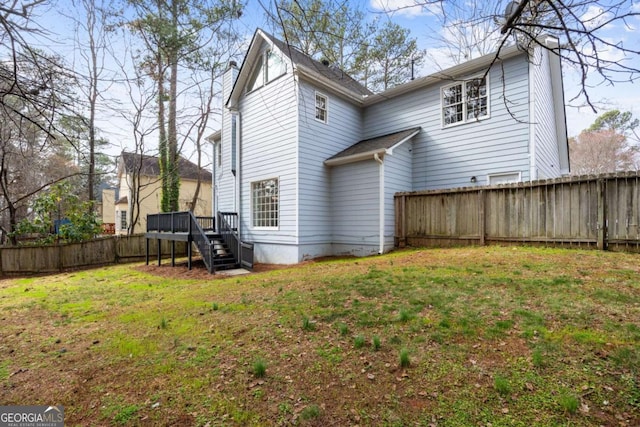 back of property with a lawn, a wooden deck, and a fenced backyard