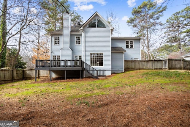 back of property featuring a fenced backyard, a yard, a chimney, and a deck