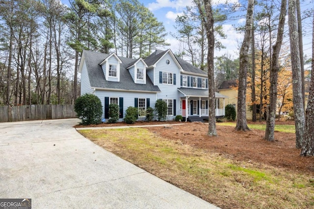 view of front of home featuring covered porch, driveway, a shingled roof, and fence