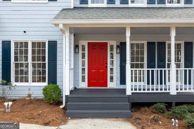 doorway to property with covered porch and roof with shingles