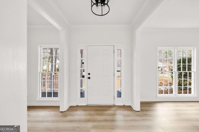 foyer entrance featuring wood finished floors, baseboards, and ornamental molding