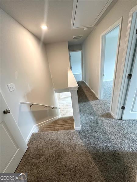 stairway featuring visible vents, baseboards, carpet, and attic access