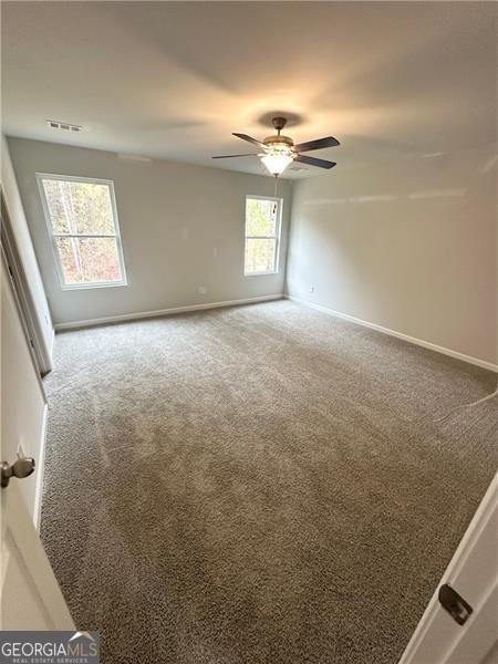 spare room with visible vents, ceiling fan, baseboards, and carpet