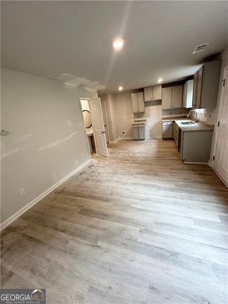 kitchen featuring baseboards, light wood finished floors, recessed lighting, a sink, and open floor plan